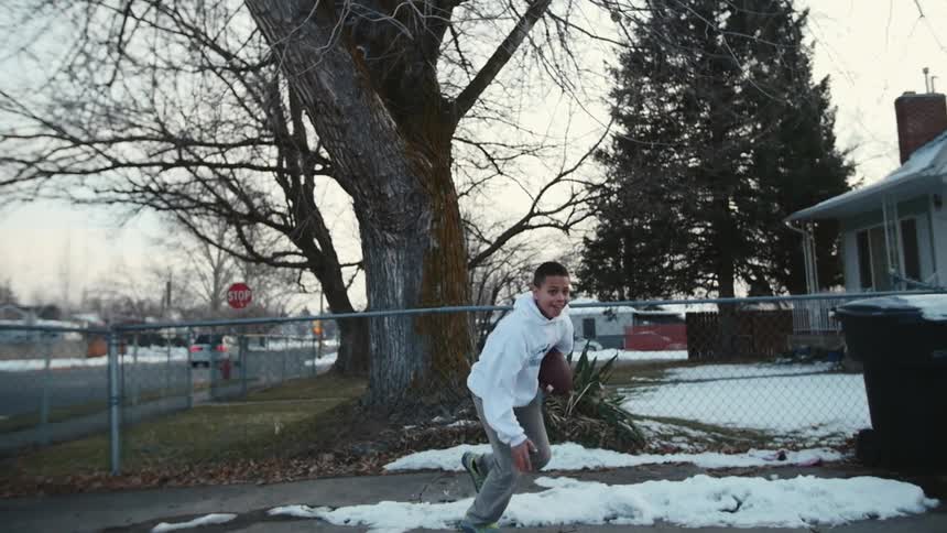 A boy playing rugby in front of his house at winter season