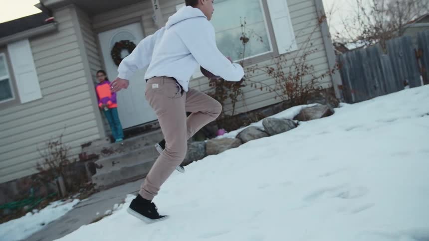 Boys playing football in a snow-covered front yard