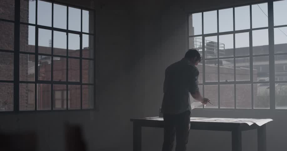 A man that is grabbing a piece of paper on a table