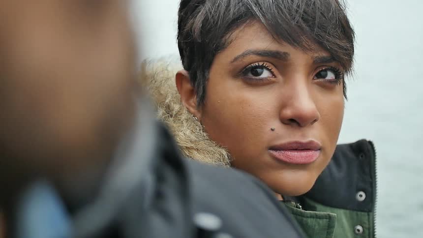 A young woman wearing a coat turns her head to look up at a man standing beside her