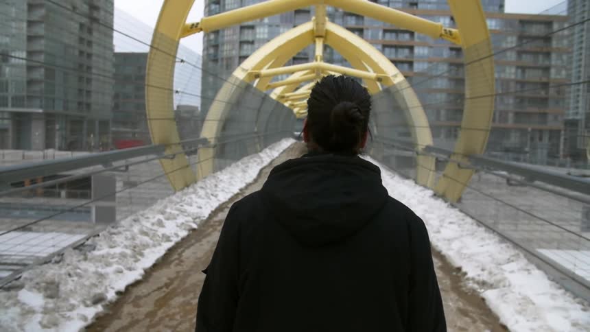 A woman walks along a city bridge on a winter day