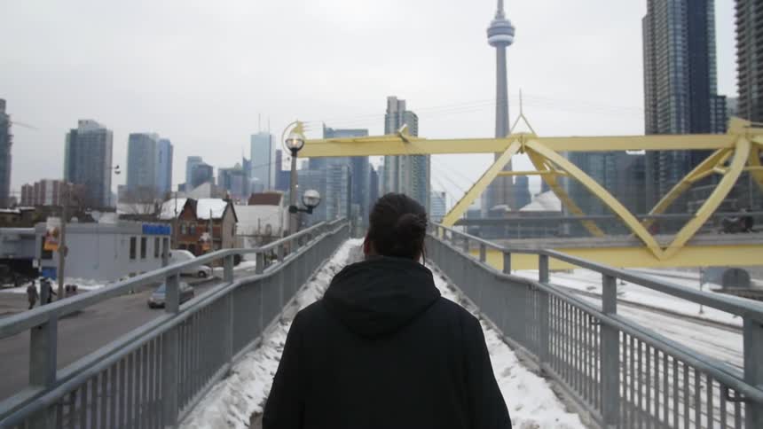 Man walking on an elevated snowy walkway towards a large city