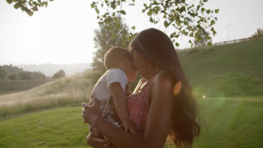 A woman with long dark hair touches her forehead to her child's