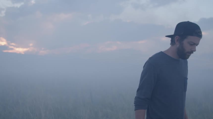 A man walking through a smoky field at sunset