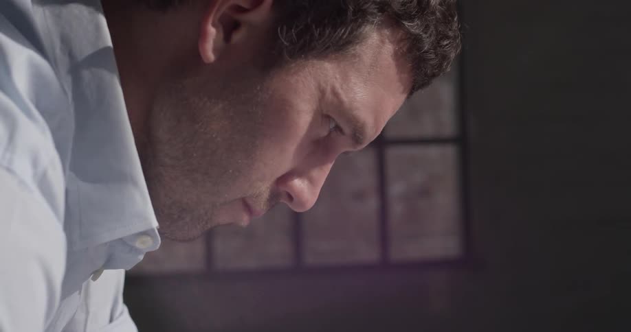 A man in a white shirt looks down at something