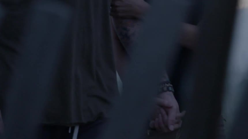 A man and woman walk holding hands