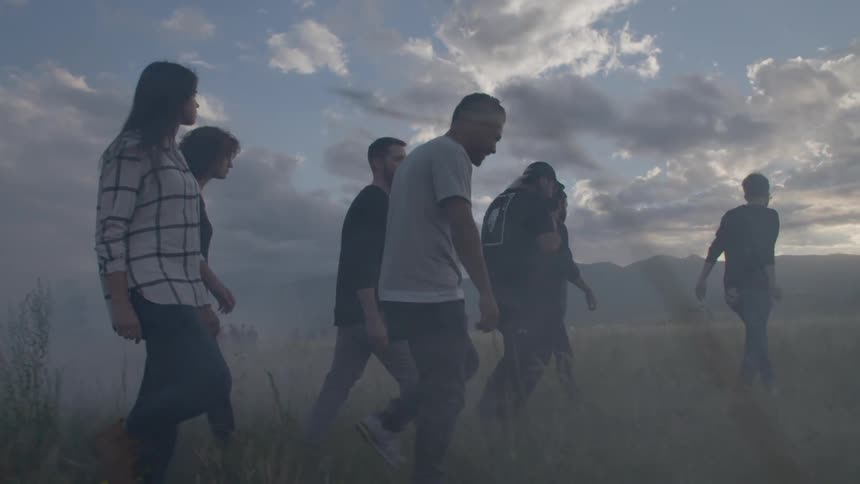 A group of young people walk through a foggy field