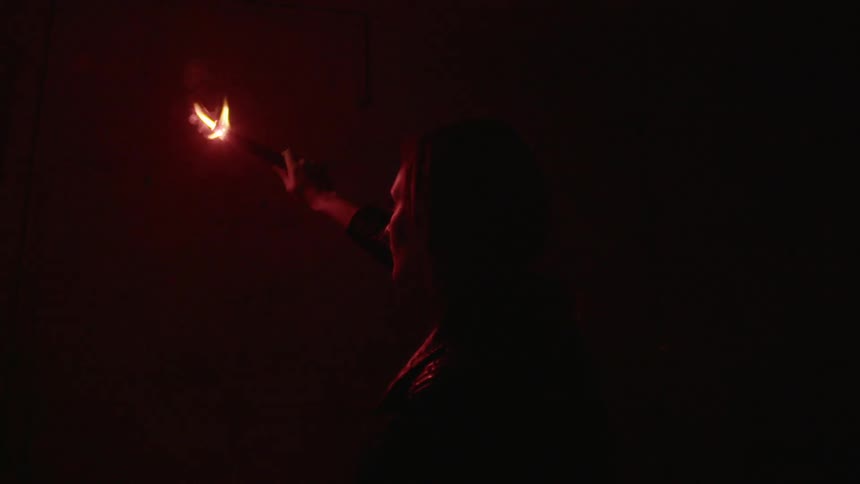A woman holding a flare up to a wall