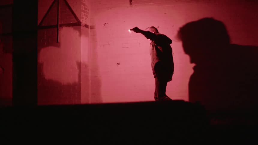 A man holds a flame by his head as he walks outside at night