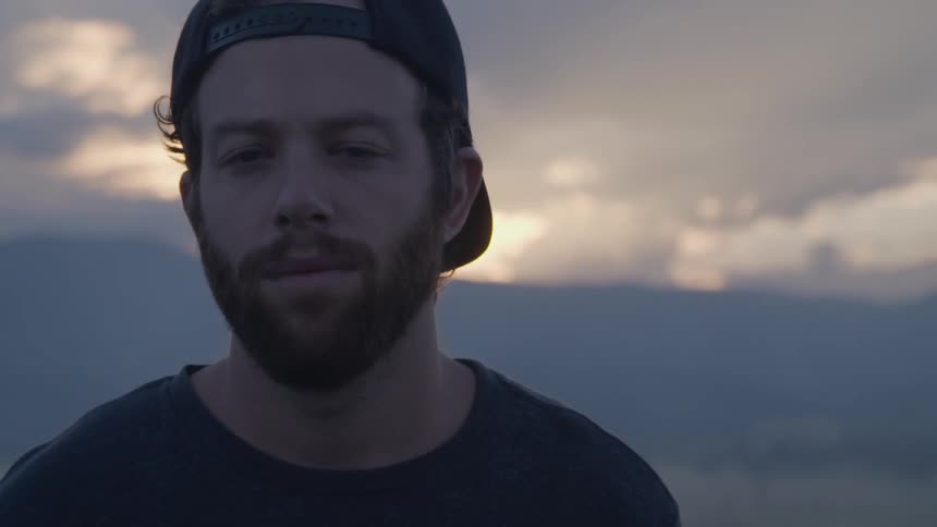 A man is standing outdoors as the sun is setting