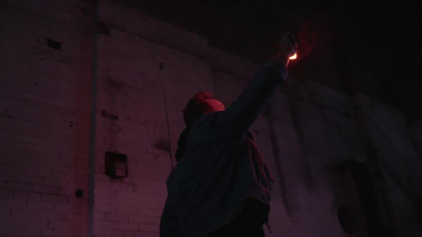 A man uses a flare to light the walls of an abandoned building