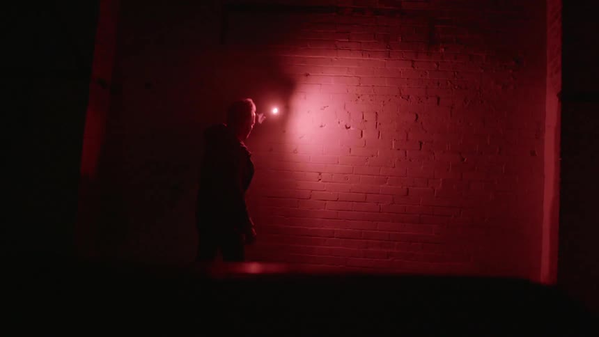 A man holding a flare up to a brick wall