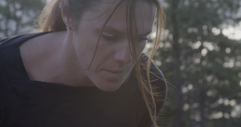 A woman in a black shirt standing in front of some trees