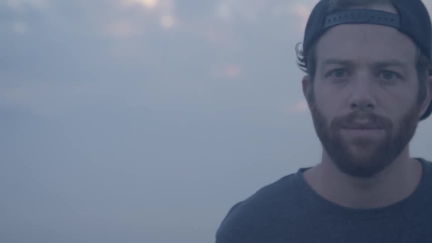 A man in a backwards baseball cap standing outside
