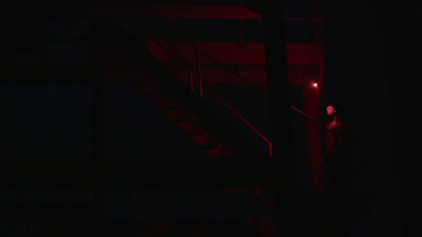 Woman waves a red emergency flare inside a dark basement