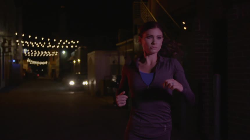A woman running down a city street at night