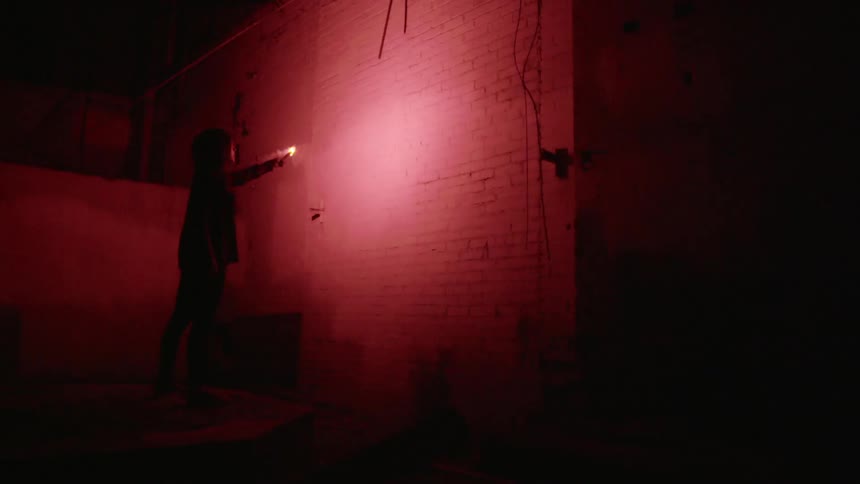 A woman is looking at a wall in red light