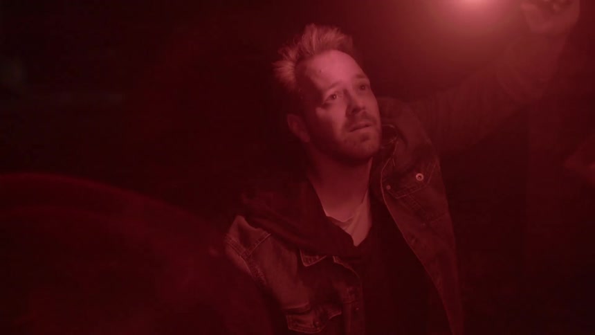 A man is standing outdoors at night with a flame