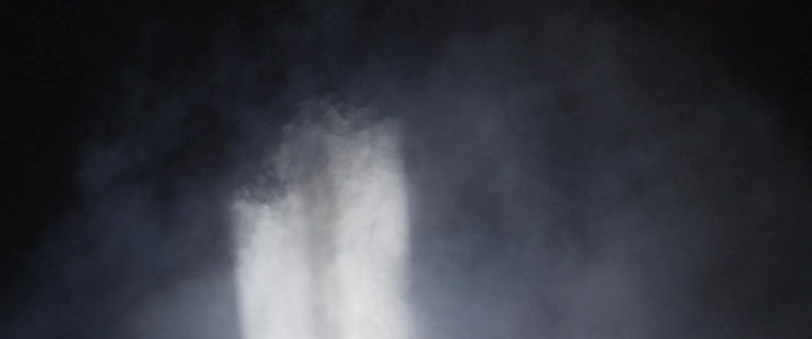 Two light beams shine down through smoke against a dark background