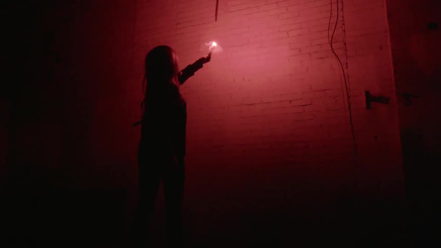 A woman holding a candle up to a brick wall