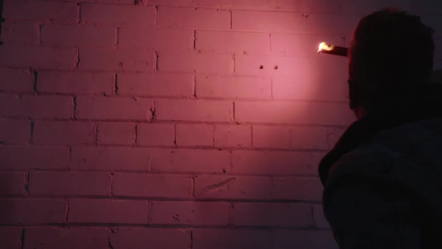A person holding a flare to light up a brick wall
