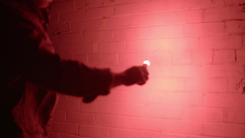 A man holding a flare up to a brick wall