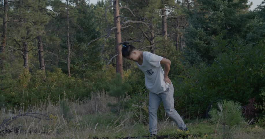 A man is stretching outdoors in the forest