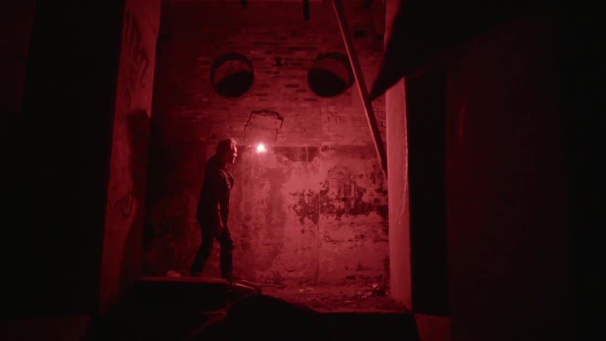 A man uses a flare to light his way in an abandoned building