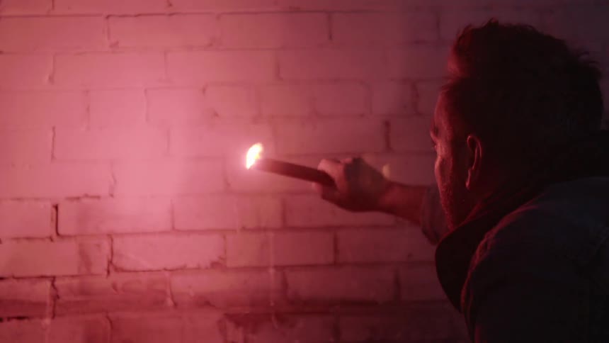 A man holding a flare up to a brick wall