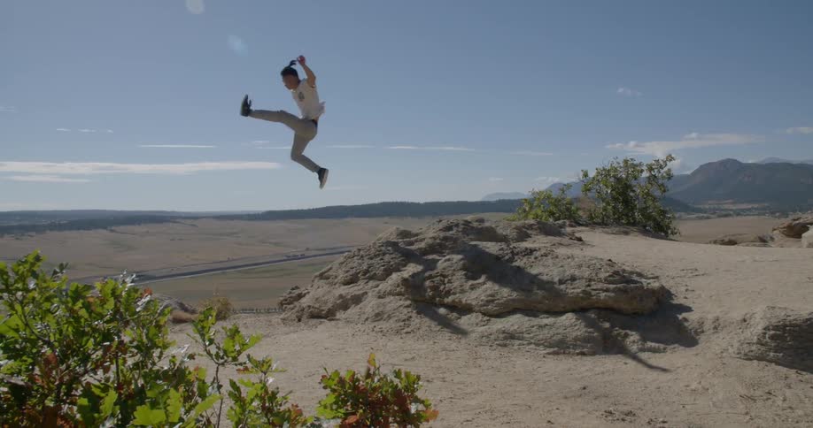 A young man running up to the edge of rocks and jumping off