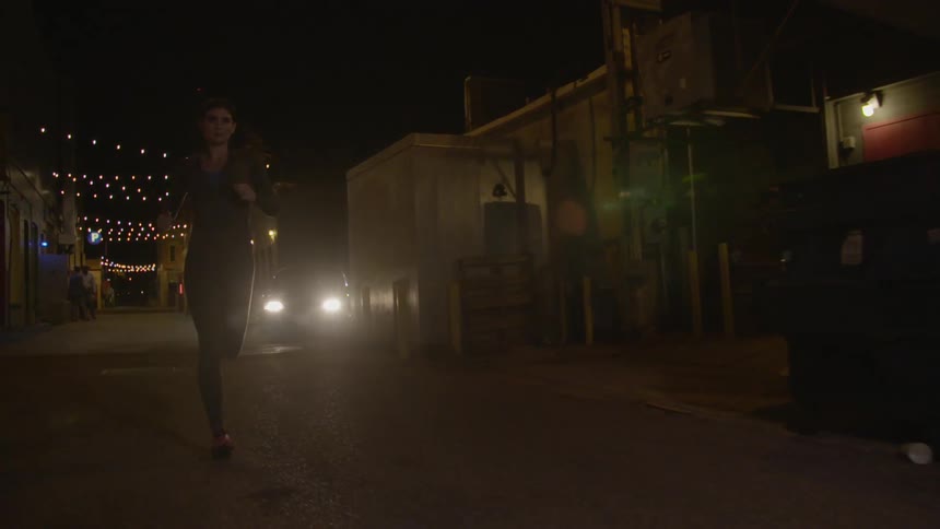 A woman jogging in an urban area at night