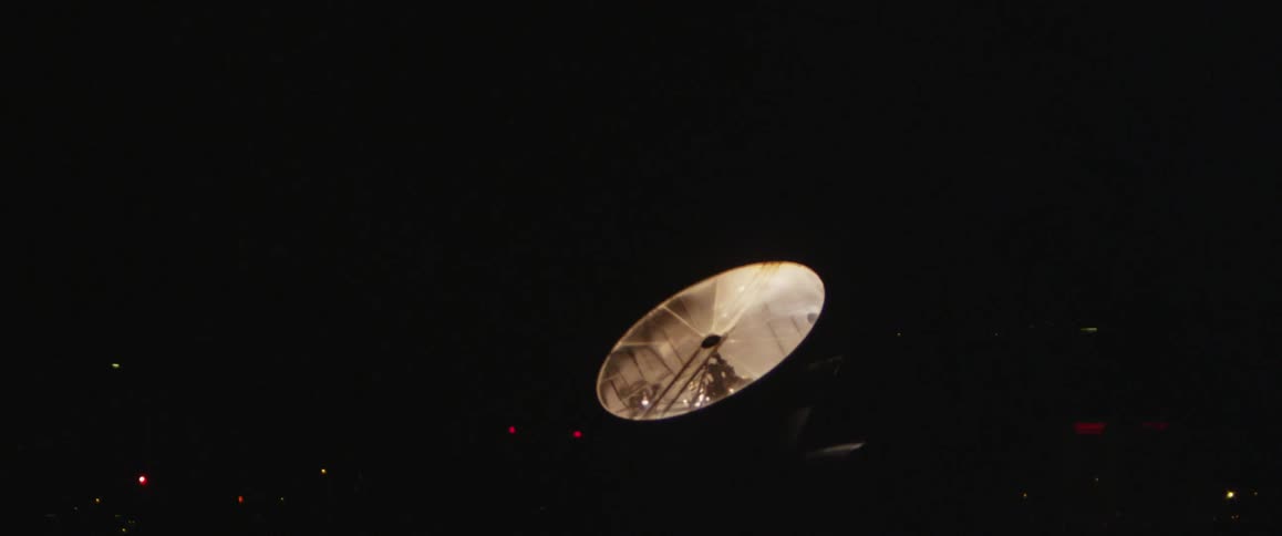A spotlight ignites against a dark night sky