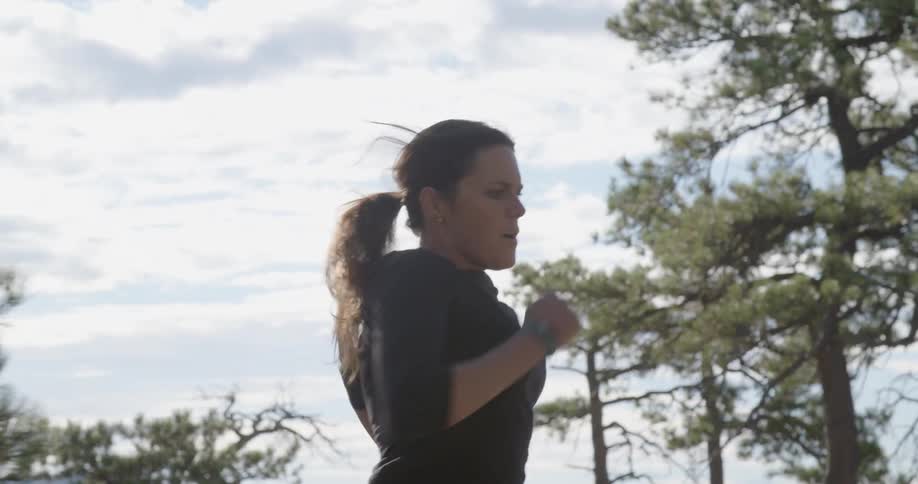 A woman runs through the woods on a dirt path