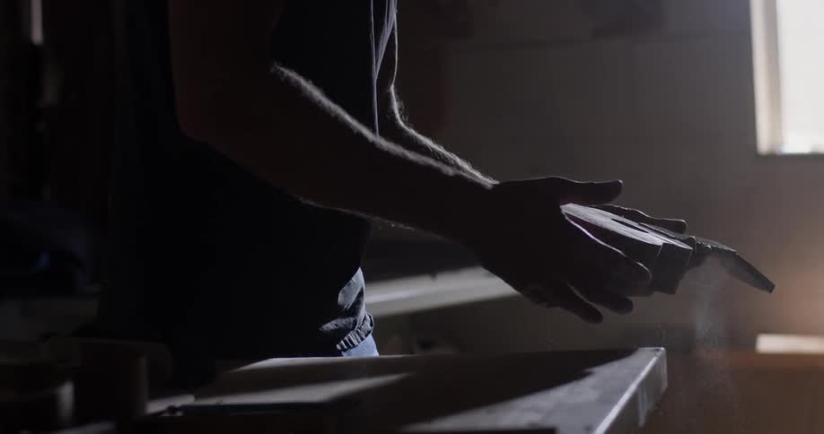A man brushes off a ukulele and then blows on it