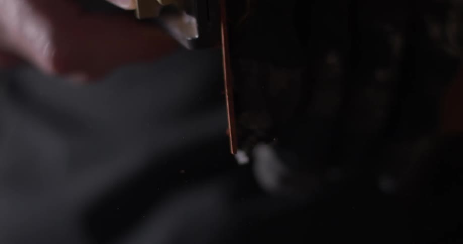 A man uses sandpaper on a piece of wood in a dark garage
