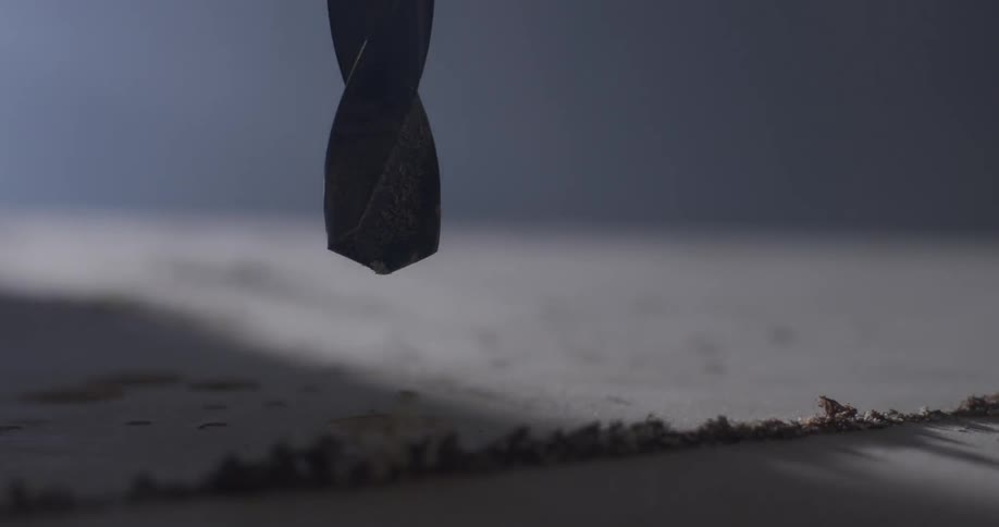 A drill bit sits right above a piece of wood