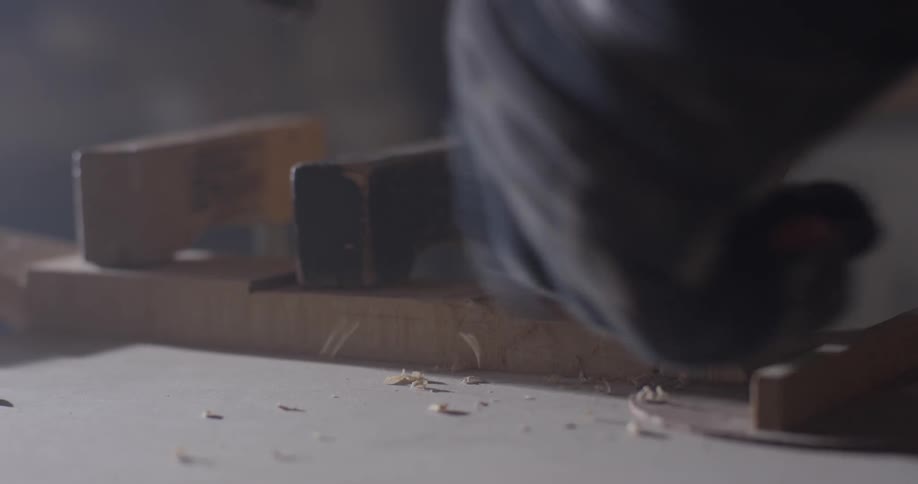 Hand uses tool to shave down wood