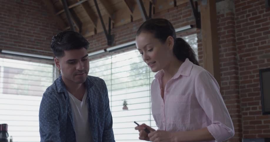 A man and woman talking about something on a tablet