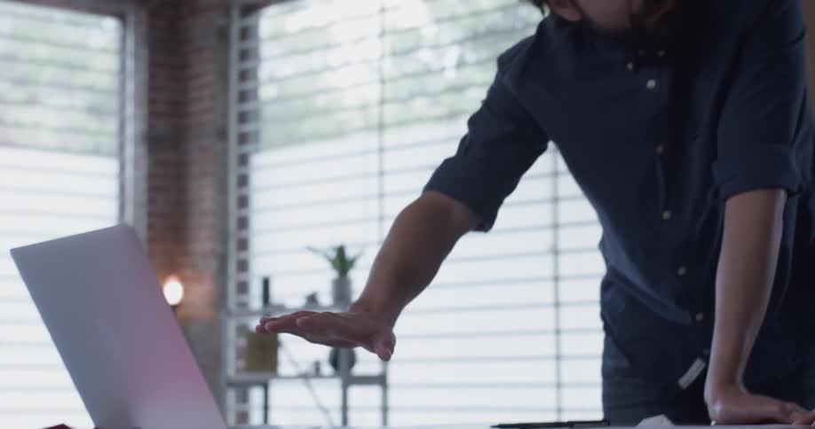 Two men pointing and talking while looking at a laptop