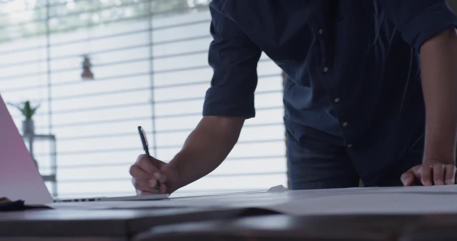 A man leaving over a table writing
