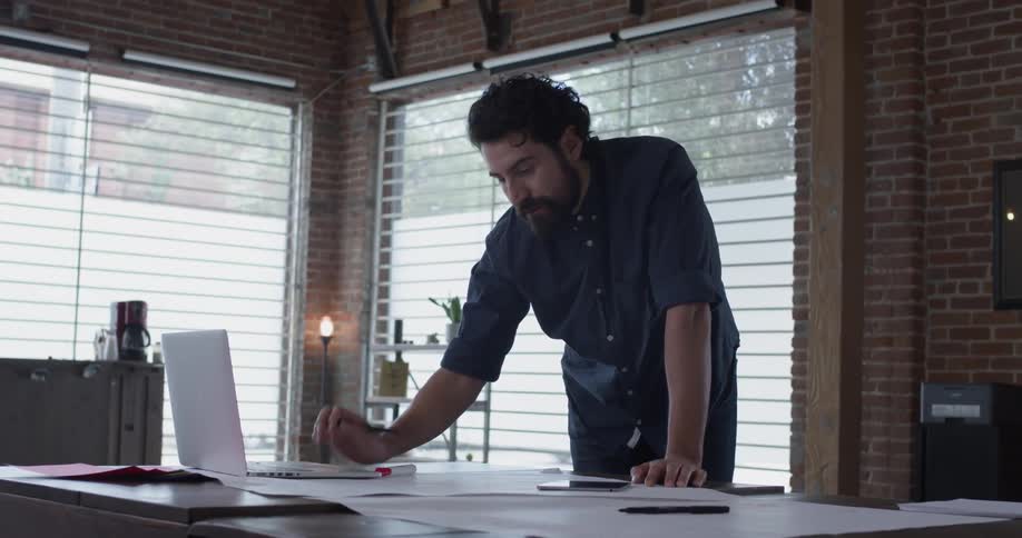 Man writes on paper and types on laptop on table