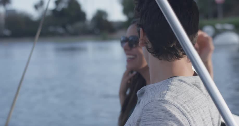 A couple in sunglasses laughs while in a paddleboat on a lake