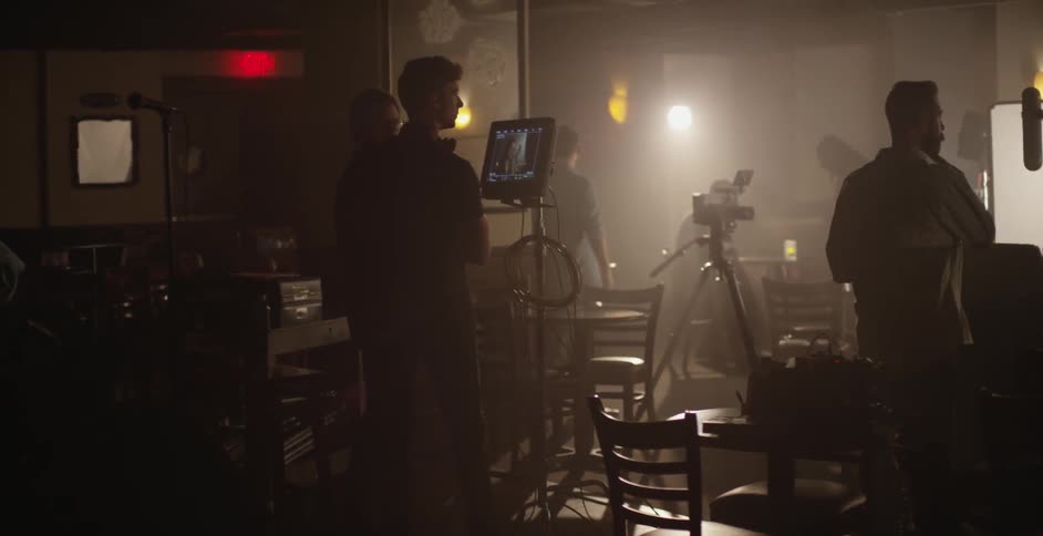 People standing in a dim bar prepare to make a video recording