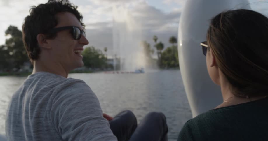 A man and woman lean in for a kiss on a swan shaped boat