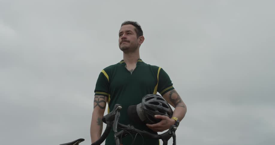 A man stands by his bike looking into the distance