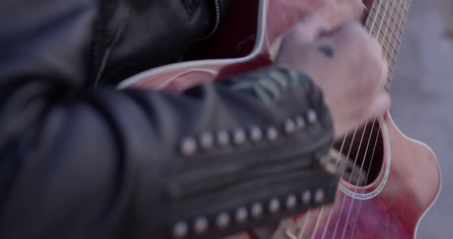 A person strumming a guitar out on a street