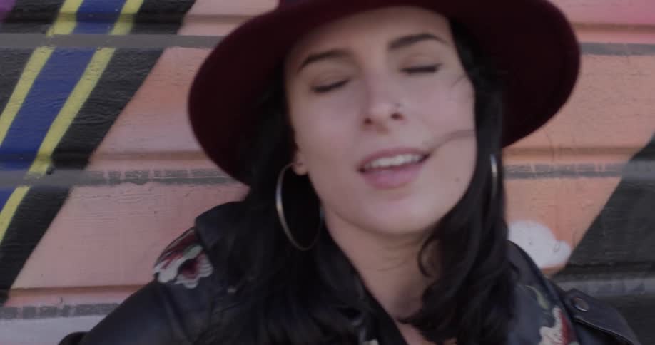 Woman singing swaying with guitar by graffiti wall