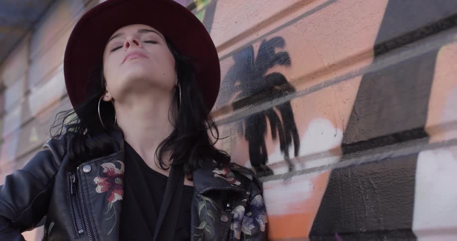 A woman wearing a hat is smiling outside