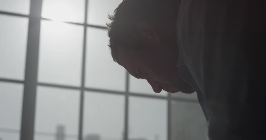 A man standing in front of a window reading a piece of paper