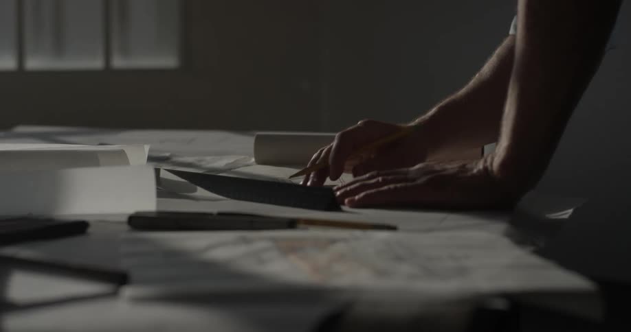 A person drawing on a piece of paper on a desk